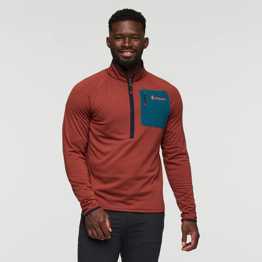 A man wearing a red half-zip fleece hooded jacket with a zippered chest pocket and thumbholes in the sleeves.