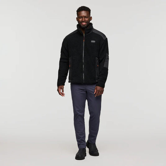Man wearing a black jacket and gray pants on a white background