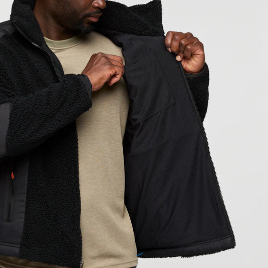 Person wearing a black jacket with a textured inner lining, holding it open to show the interior.