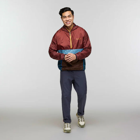 Person wearing a maroon and blue jacket with gray pants on a light gray background