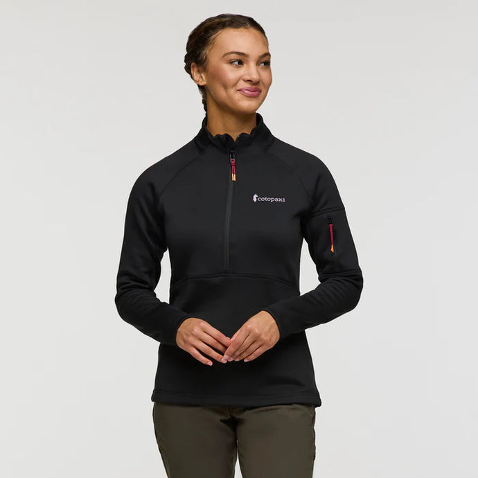 Woman wearing a black pullover with a brand logo on a gray background