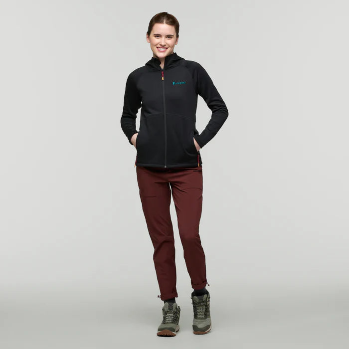 Load image into Gallery viewer, Person wearing a black jacket with a logo, maroon pants, and green boots on a light gray background
