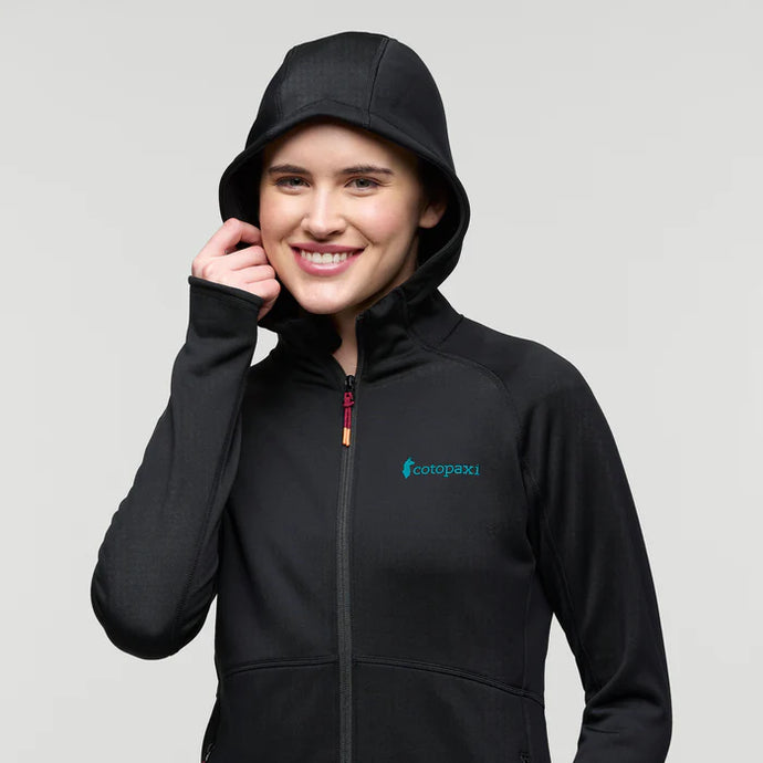 Person wearing a black hoodie with a Cotopaxi logo on a light gray background