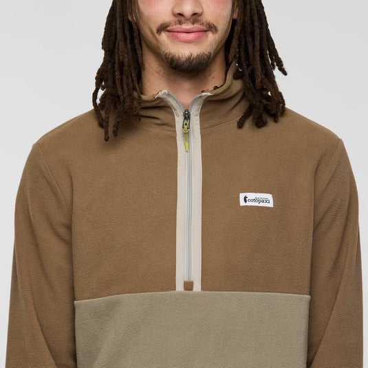 Man wearing a brown and beige pullover with a cotopaxi logo on a white background