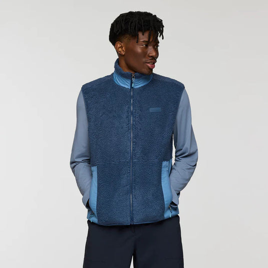 Person wearing a blue fleece vest over a light blue shirt on a white background