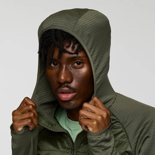 Man wearing a green hooded jacket against a plain background