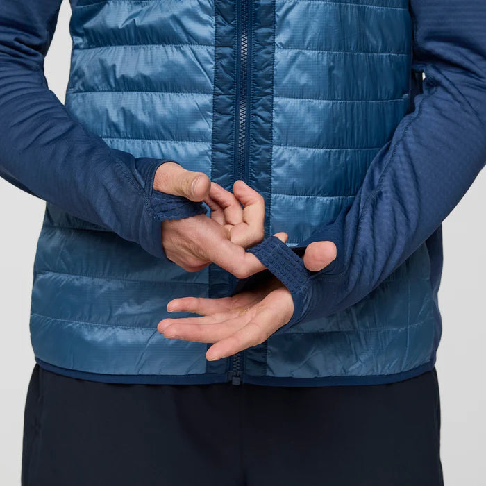 Load image into Gallery viewer, Person wearing a blue puffer jacket with thumb cuffs on a light gray background
