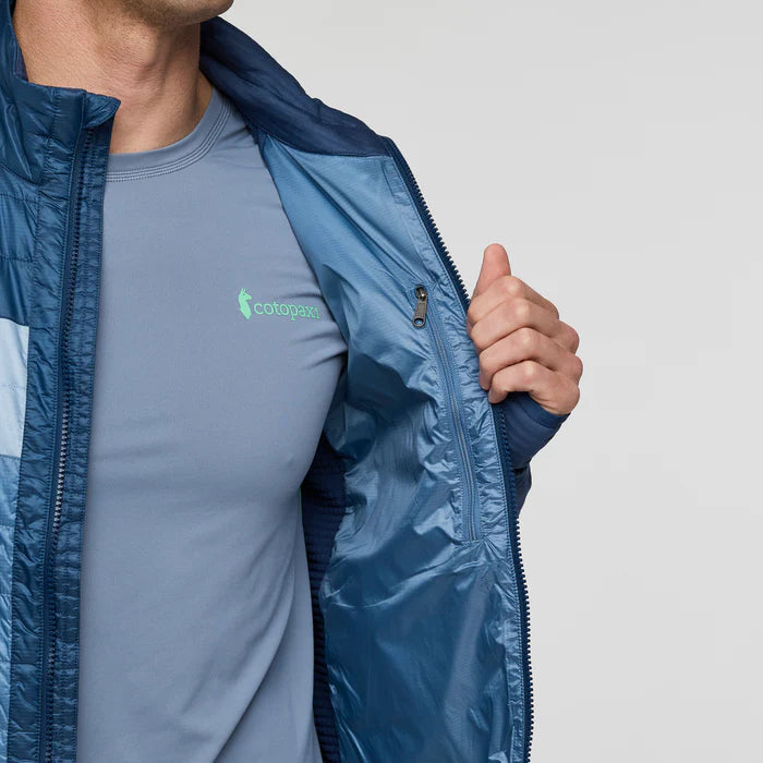 Load image into Gallery viewer, Person wearing a blue Cotopaxi zip jacket on a light gray background
