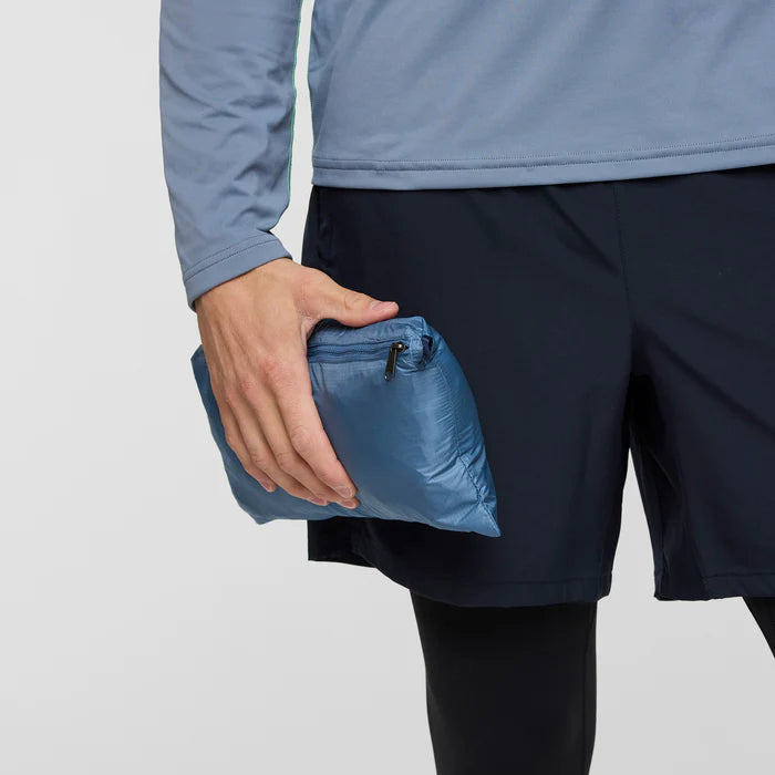 Load image into Gallery viewer, Person holding a blue compressed jacket bag against a light gray background
