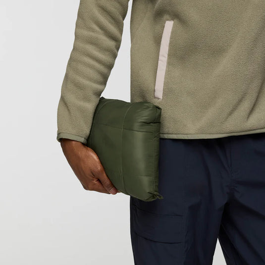 Person holding a green jacket pack against a white background