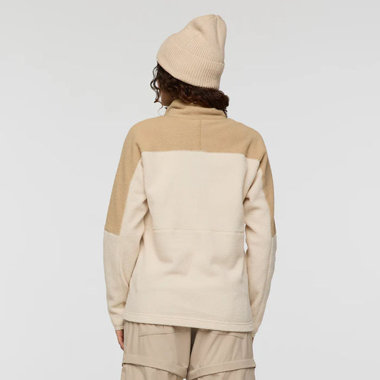 Person wearing a beige and white fleece jacket with a matching beanie on a plain background