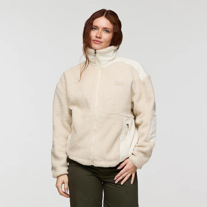 Woman wearing a cream-colored fleece jacket on a plain background