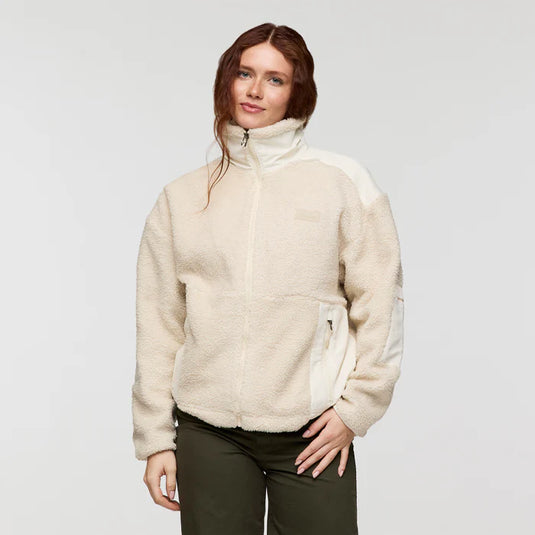 Woman wearing a cream-colored fleece jacket on a plain background