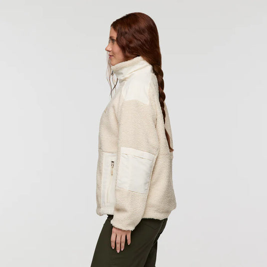 Woman wearing a cream-colored fleece jacket on a plain background