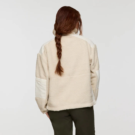 Woman wearing a cream-colored fleece jacket on a plain background
