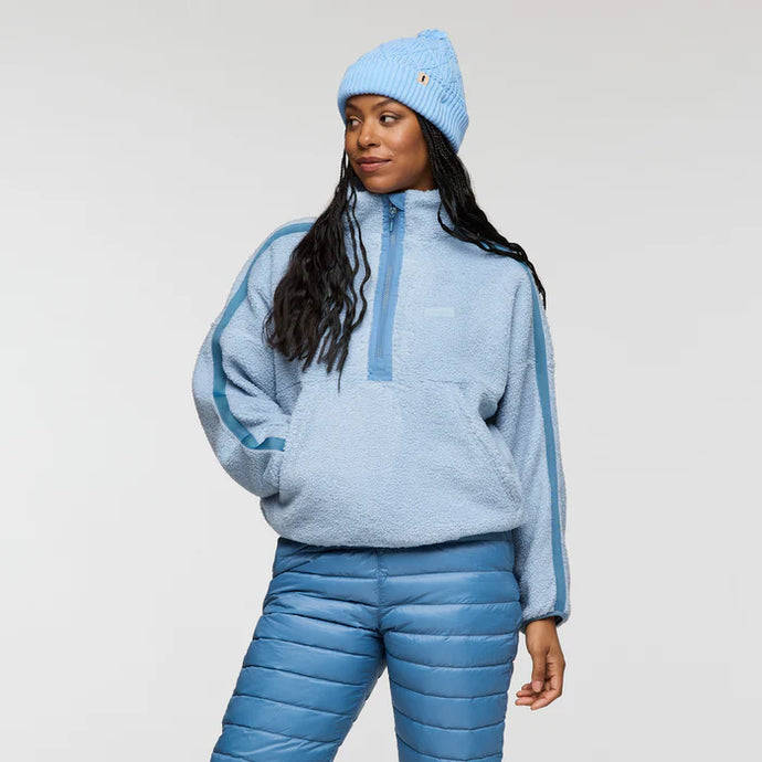 Person wearing a blue fleece pullover and pants with a matching beanie on a light gray background