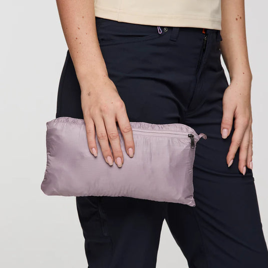 Person holding a purple compact bag against a neutral background