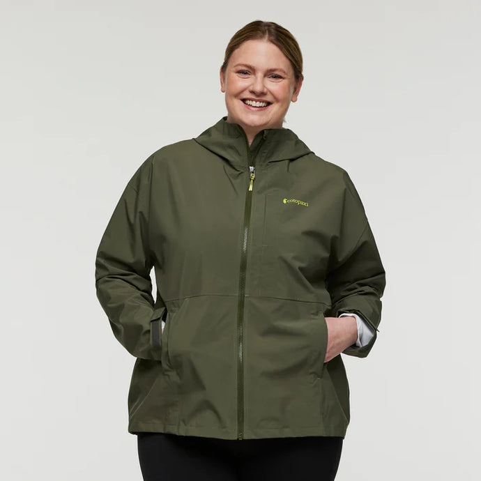 Person wearing a green jacket with a Cotopaxi logo on a plain background