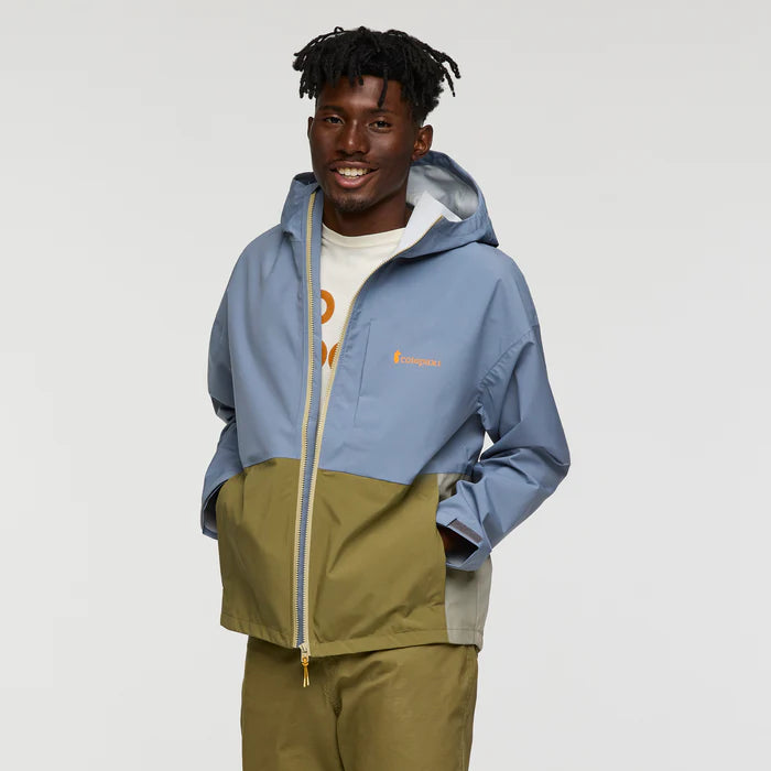 Load image into Gallery viewer, Person wearing a two-tone jacket with a Cotopaxi logo on a plain background
