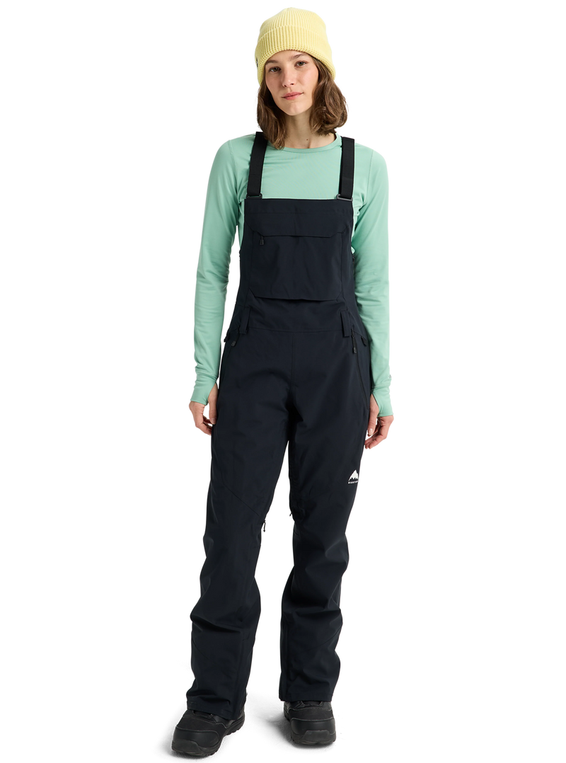 Load image into Gallery viewer, Person wearing black Burton bib overalls and a light green long-sleeve shirt on a white background Ski and Tennis Station
