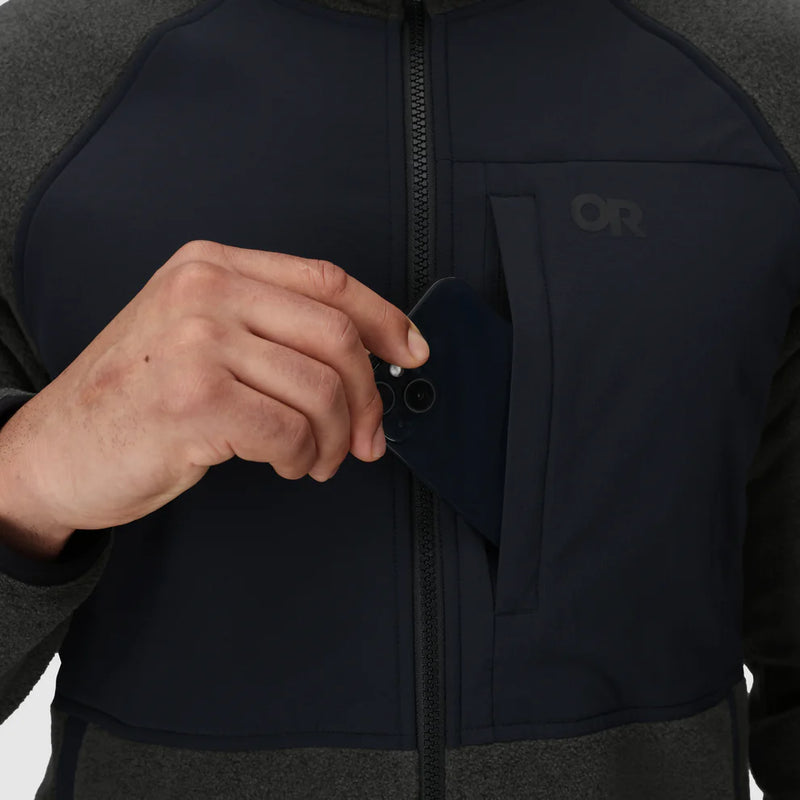 Load image into Gallery viewer, Person wearing a black Outdoor Research jacket using the phone pocket
