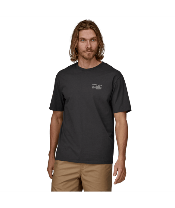 Man wearing a black t-shirt with a logo on a green background