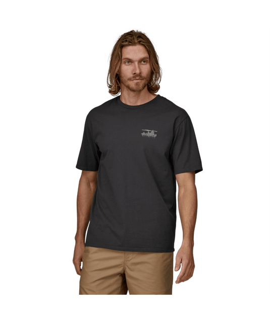 Man wearing a black t-shirt with a logo on a green background