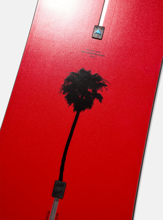 Red snowboard with black palm tree silhouette and mountain logo.