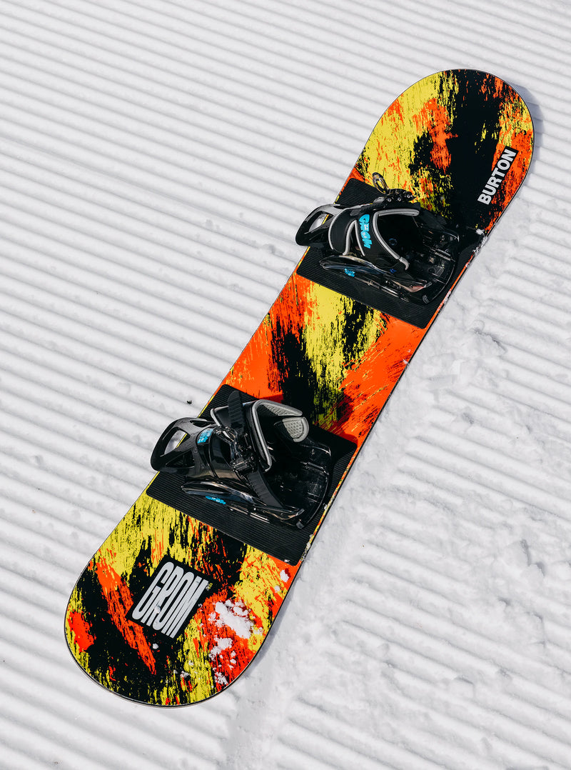 Load image into Gallery viewer, Colorful snowboard with bindings on a textured snowy surface
