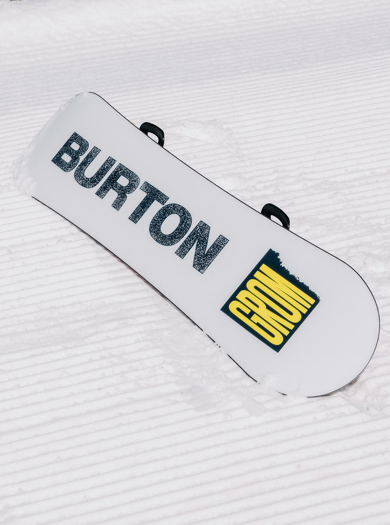 Load image into Gallery viewer, White snowboard with &#39;Burton&#39; branding on a textured snowy background
