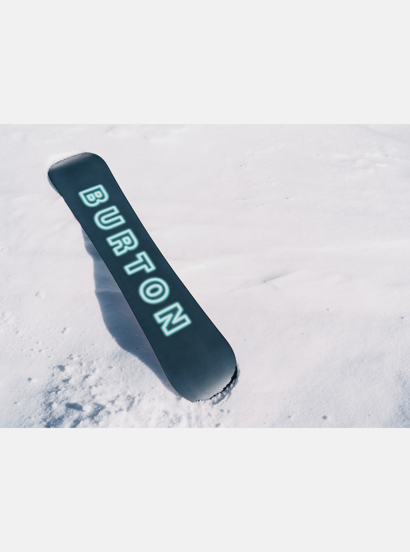 Load image into Gallery viewer, Snowboard with branding on a snow-covered surface
