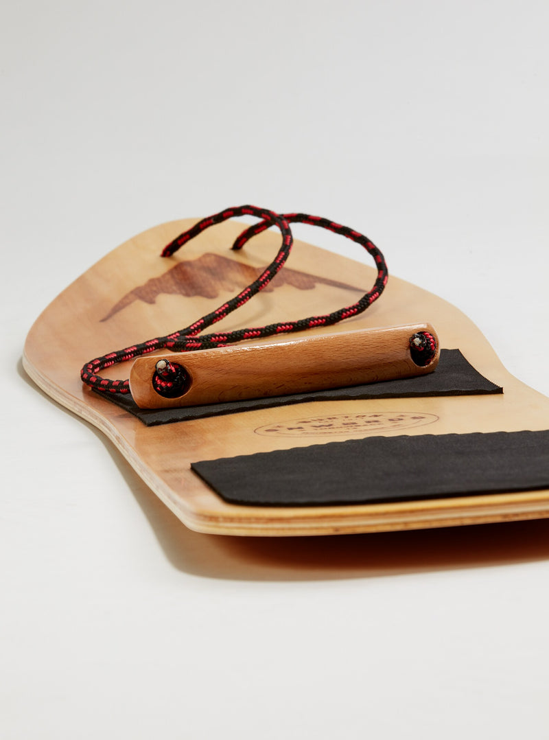 Load image into Gallery viewer, Wooden snowboard with black grip and red cord on a light background
