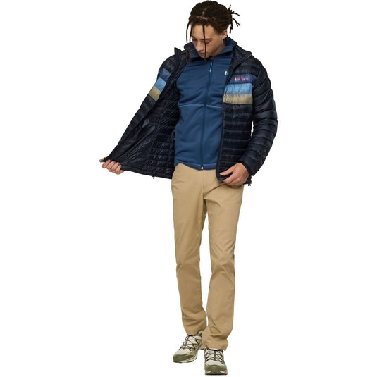 Person wearing a blue and navy jacket with beige pants on a white background