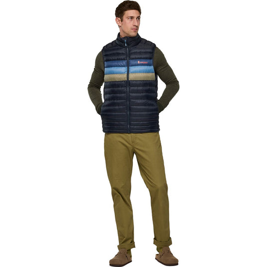 Man wearing a striped puffer vest and green pants on a white background