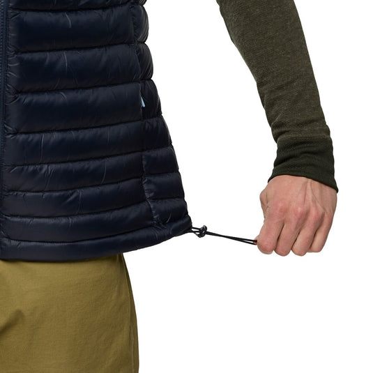 Person wearing a navy puffer vest with a white background