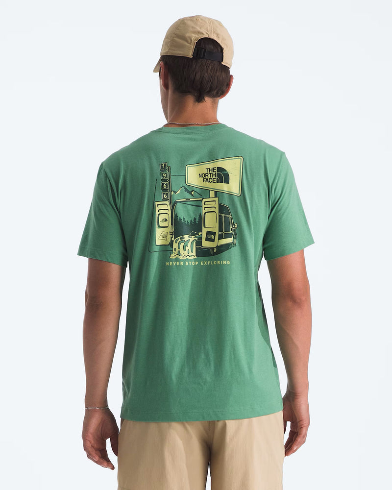 Load image into Gallery viewer, A man wearing a dimmed alage short-sleeve t-shirt from The North Face with a large graphic print on the back, paired with khaki pants and a beige baseball cap. Ski and Tennis Station
