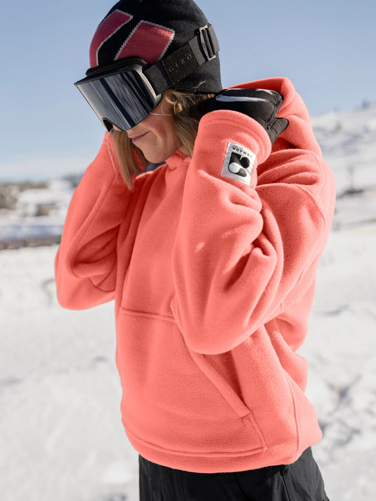 Person wearing a pink hoodie with a brand logo in a snowy landscape