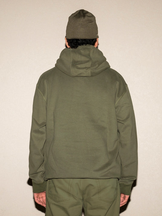 Person wearing a green jacket and pants on a plain background