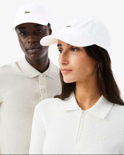 Two people wearing white caps with a Lacoste logo on a white background
