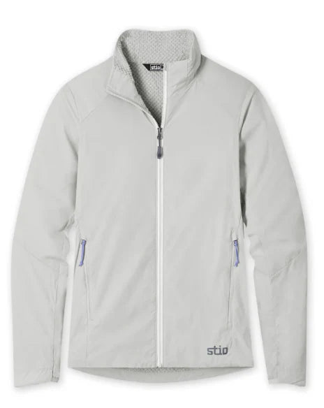 A light gray zip-up jacket with a stand-up collar, zippered hand pockets, and a small Stio brand logo near the bottom hem. Ski and Tennis Station