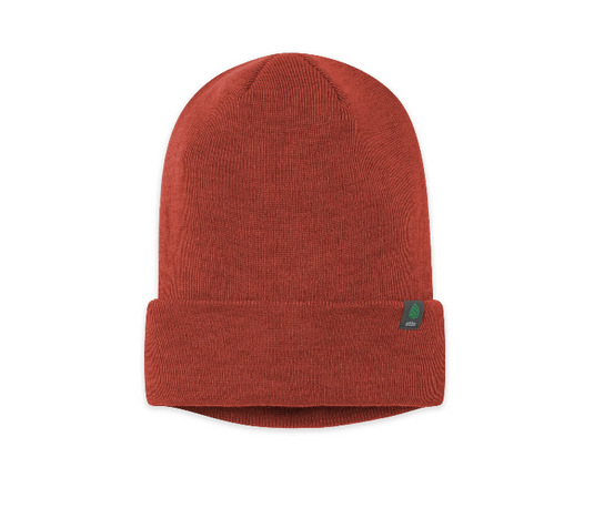 A rust-colored ribbed knit beanie hat with a folded cuff and a small green Stio tag on the side. Ski and Tennis Station