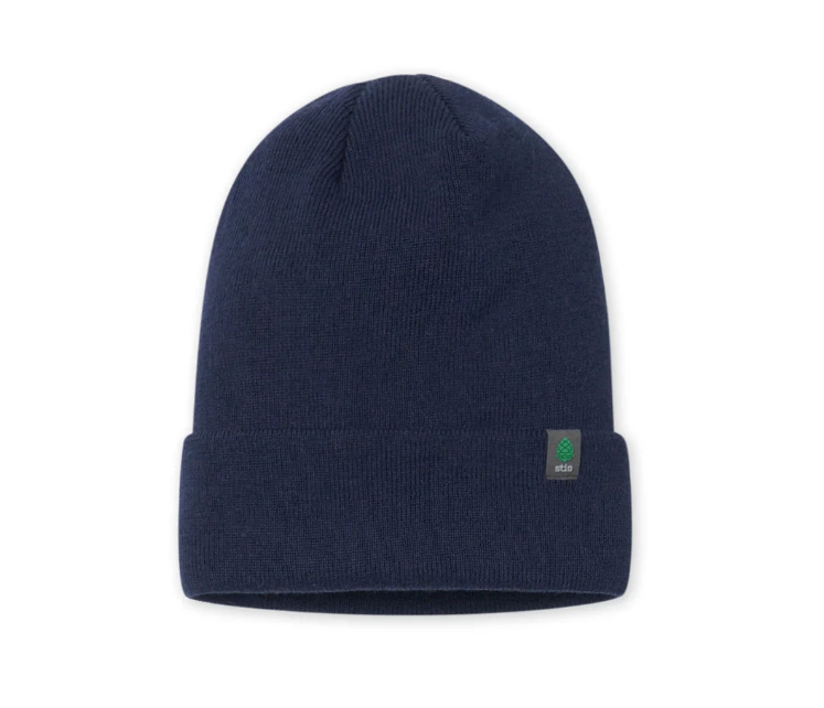 Load image into Gallery viewer, A navy blue knit beanie hat with a folded cuff, featuring a small green and white Stio logo patch on the right side of the cuff. Ski and Tennis Station

