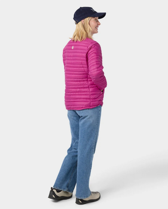 A woman wearing a bright pink Stio puffer jacket with a high collar and front zipper. Ski and Tennis Station