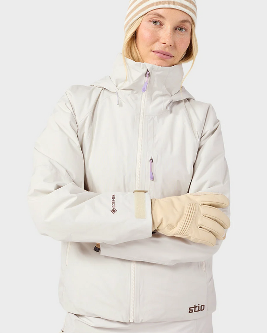 A model wearing a light beige/cream Stio ski jacket, matching ski pants. Ski and Tennis Station.