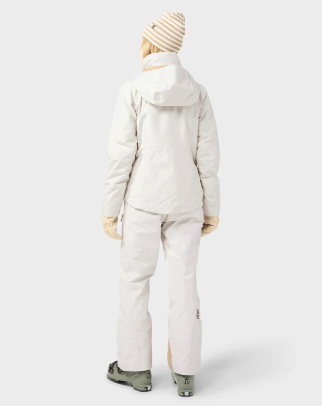 Load image into Gallery viewer, A model wearing a light beige/cream Stio ski jacket, matching ski pants. Ski and Tennis Station.
