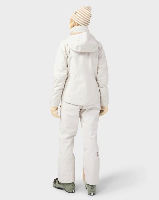 A model wearing a light beige/cream Stio ski jacket, matching ski pants. Ski and Tennis Station.