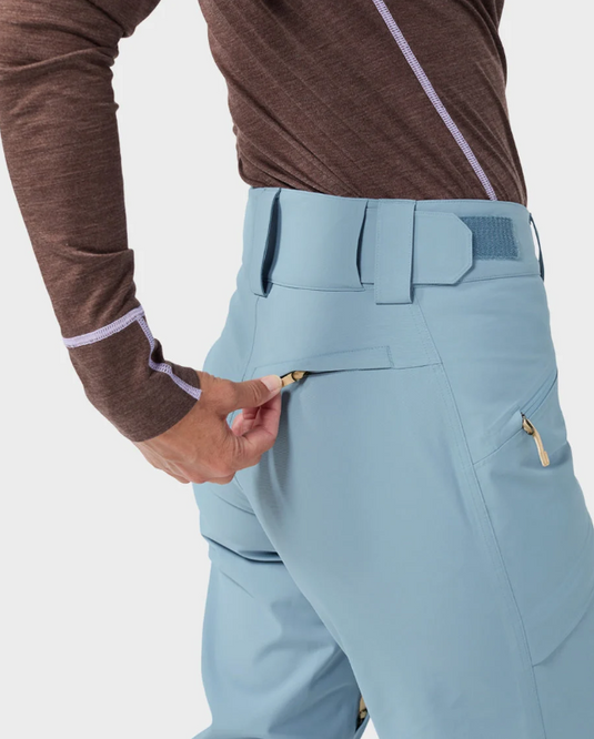 A model wearing light blue and white color-blocked Stio skyrider ski pants with a brown long-sleeve top. Ski and Tennis Station