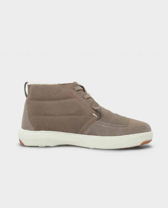 A single mid-cut lace-up Stio shoe in taupe brown suede and canvas, featuring a thick white sole and a small orange accent on the outsole. Ski and Tennis Station
