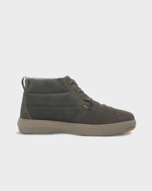A single mid-cut lace-up Stio shoe in dark olive green suede and fabric, featuring a thick tan sole. Ski and Tennis Station