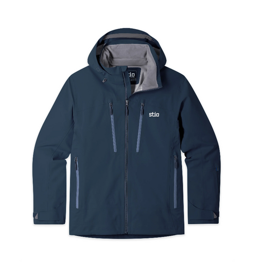 A dark navy blue hooded Stio Environ jacket with a gray interior lining, featuring the white 'stio' logo on the left chest. Ski and Tennis Station